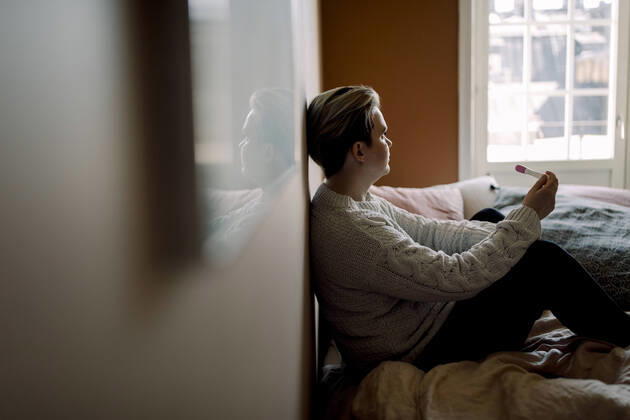 IMAGO Creative: 2022 Favoriten Side view of upset woman holding pregnancy test result sitting on bed at home Sweden, Stockholm, model released, property released Copyright: xMaskotx , MA94139