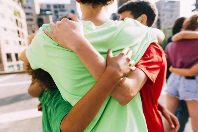 IMAGO Creative: Welttag für psychische Gesundheit am 10. Oktober Multiracial friends hugging each other standing on footpath model released, Symbolfoto, MEUF06150