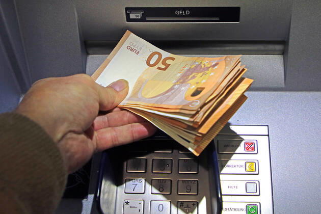 Bargeldversorgung aus einem Automat Eine Person holt an einem Geldautomaten eine größere Menge Bargeld in 50 Euro Geldscheinen ab
