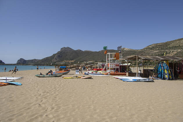 Tourism In Greece - Falassarna Beach In Crete Island Tourism in Greece - Water sports and lifeguard tower. The exotic beach of Falassarna at the western side of Crete island. Falasarna bay with 5 beaches with whitish sand and crystal clear transparent tropical turquoise water hosts some of the most famous beaches in Greece, which has been awarded as the best beach of Crete and voted as one of the 10 best beaches in Europe several times in the past. Local people and tourists are seen relaxing, sunbathing, tanning, swimming, doing water sports and walking. Tourism is bouncing back with reservations exceeding the pre-pandemic numbers, putting Greece and the Greek islands on high demand. Tourists travel after the Covid-19 Coronavirus pandemic. Copyright: xNicolasxEconomoux originalFilename: economou-tourismi220614_npvVs