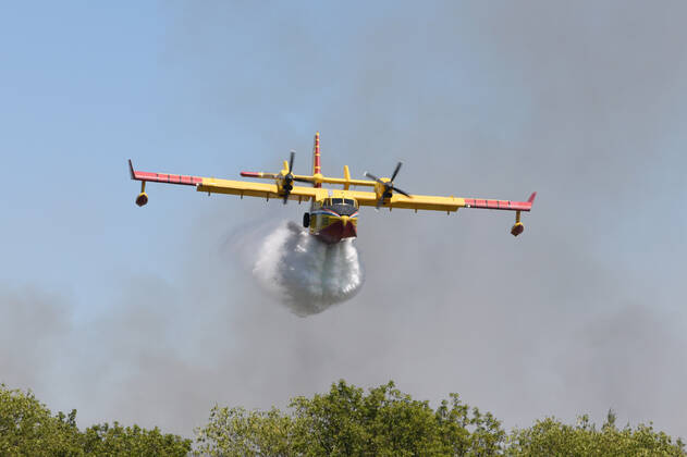 PXL_A fire near Vodice, Croatia Fire in an open area near the Velika Mrdakovica archaeological site in the Vodice hinterland, Croatia on July 13, 2022. About 30 firefighters with a dozen vehicles are on the ground, and two Canadairs joined the ground forces in extinguishing the fire. There are pine forests above, low vegetation, and endangered buildings. HrvojexJelavic PIXSELL