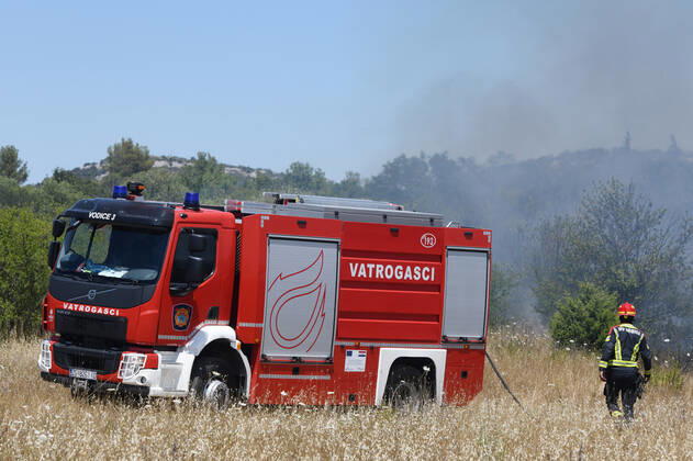 PXL_A fire near Vodice, Croatia Fire in an open area near the Velika Mrdakovica archaeological site in the Vodice hinterland, Croatia on July 13, 2022. About 30 firefighters with a dozen vehicles are on the ground, and two Canadairs joined the ground forces in extinguishing the fire. There are pine forests above, low vegetation, and endangered buildings. HrvojexJelavic PIXSELL