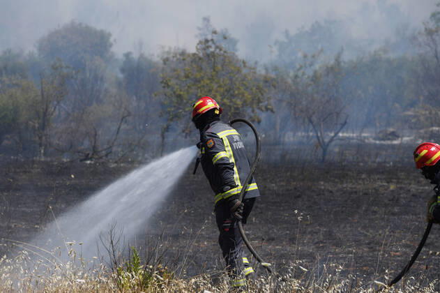 PXL_A fire near Vodice, Croatia Fire in an open area near the Velika Mrdakovica archaeological site in the Vodice hinterland, Croatia on July 13, 2022. About 30 firefighters with a dozen vehicles are on the ground, and two Canadairs joined the ground forces in extinguishing the fire. There are pine forests above, low vegetation, and endangered buildings. HrvojexJelavic PIXSELL