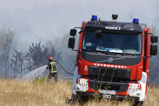 PXL_A fire near Vodice, Croatia Fire in an open area near the Velika Mrdakovica archaeological site in the Vodice hinterland, Croatia on July 13, 2022. About 30 firefighters with a dozen vehicles are on the ground, and two Canadairs joined the ground forces in extinguishing the fire. There are pine forests above, low vegetation, and endangered buildings. HrvojexJelavic PIXSELL