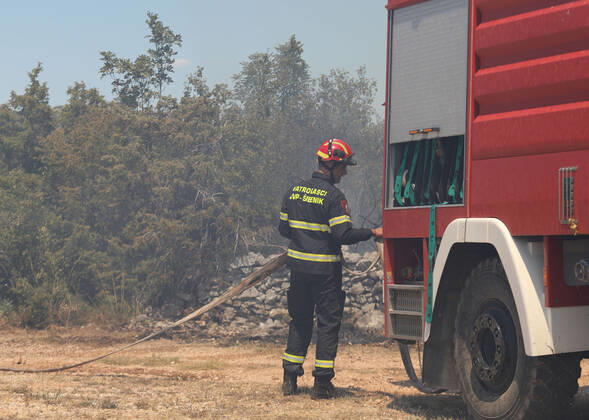 PXL_A fire near Vodice, Croatia Fire in an open area near the Velika Mrdakovica archaeological site in the Vodice hinterland, Croatia on July 13, 2022. About 30 firefighters with a dozen vehicles are on the ground, and two Canadairs joined the ground forces in extinguishing the fire. There are pine forests above, low vegetation, and endangered buildings. DuskoxJaramaz PIXSELL