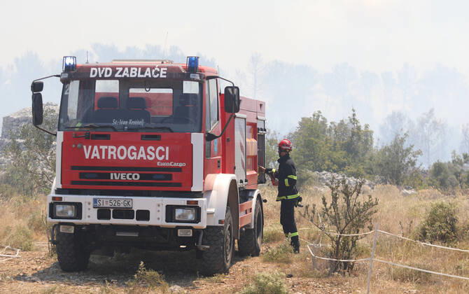 PXL_A fire near Vodice, Croatia Fire in an open area near the Velika Mrdakovica archaeological site in the Vodice hinterland, Croatia on July 13, 2022. About 30 firefighters with a dozen vehicles are on the ground, and two Canadairs joined the ground forces in extinguishing the fire. There are pine forests above, low vegetation, and endangered buildings. DuskoxJaramaz PIXSELL
