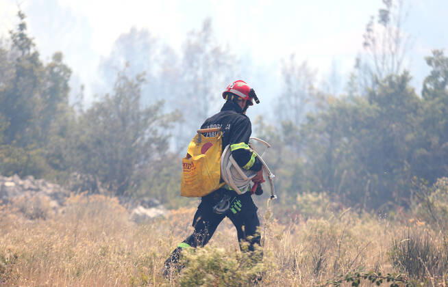 PXL_A fire near Vodice, Croatia Fire in an open area near the Velika Mrdakovica archaeological site in the Vodice hinterland, Croatia on July 13, 2022. About 30 firefighters with a dozen vehicles are on the ground, and two Canadairs joined the ground forces in extinguishing the fire. There are pine forests above, low vegetation, and endangered buildings. DuskoxJaramaz PIXSELL