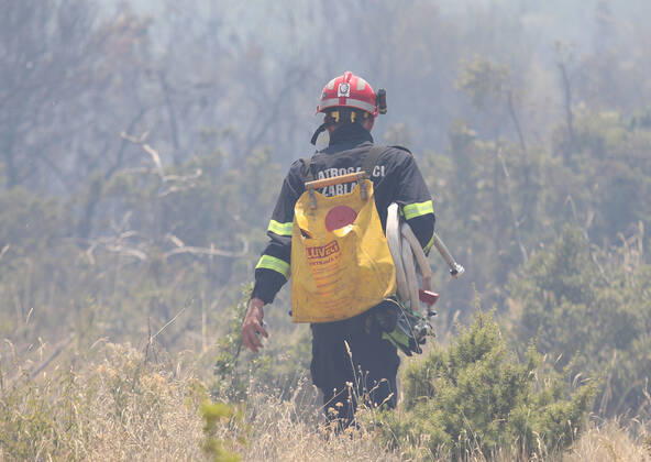 PXL_A fire near Vodice, Croatia Fire in an open area near the Velika Mrdakovica archaeological site in the Vodice hinterland, Croatia on July 13, 2022. About 30 firefighters with a dozen vehicles are on the ground, and two Canadairs joined the ground forces in extinguishing the fire. There are pine forests above, low vegetation, and endangered buildings. DuskoxJaramaz PIXSELL