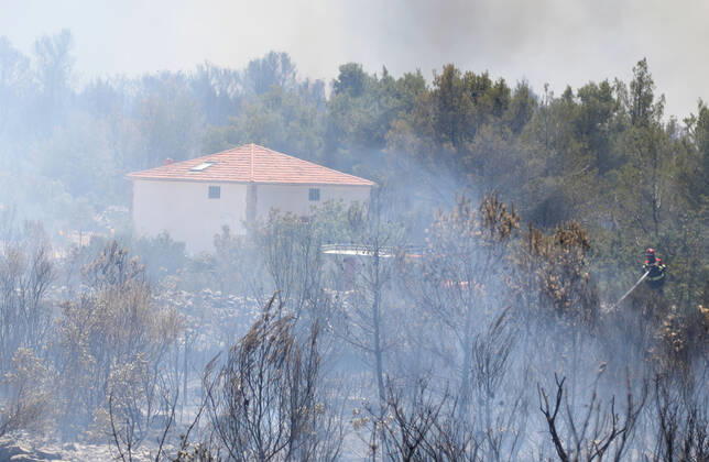 PXL_A fire near Vodice, Croatia Fire in an open area near the Velika Mrdakovica archaeological site in the Vodice hinterland, Croatia on July 13, 2022. About 30 firefighters with a dozen vehicles are on the ground, and two Canadairs joined the ground forces in extinguishing the fire. There are pine forests above, low vegetation, and endangered buildings. DuskoxJaramaz PIXSELL