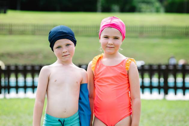Adorable little sister and brother in swimwear and hats standing on green grassy lawn at poolside and looking at camera during summer vacation, Model released HodeiUnzueta_ChildrenAndGrandfatherInPool_24.jpg Copyright: xHodeixUnzuetax MR