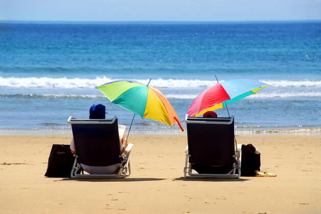 A couple relaxing on a beach under colorful umbrellas Copyright: ElenaxElisseeva 30220713