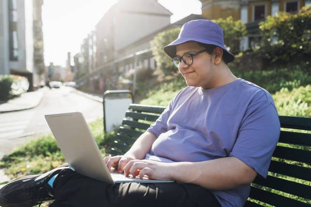 Smiling teenage boy using laptop on bench in park model released, Symbolfoto, MEUF07370