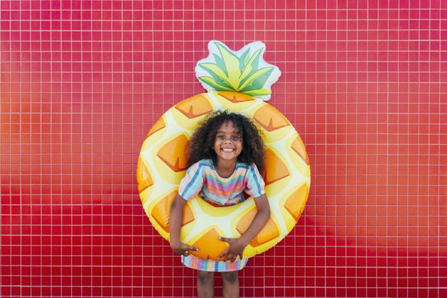 Cute girl wearing swimming float standing in front of red wall model released, Symbolfoto, OIPF02207