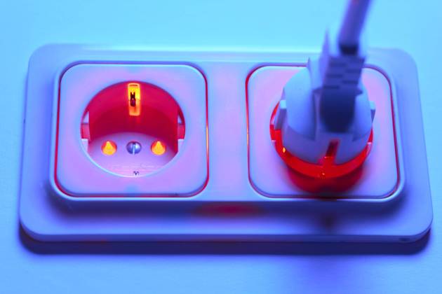 Droht im Winter die Überlastung des Stromnetzes durch den Anschluß von zu vielen Heizlüftern? Rot leuchtende Steckdose mit Schuko Stecker Energiepreise - Strom, Bonn, Deutschland am 28.08.2022