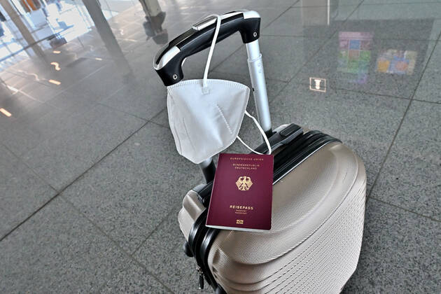 Auf dem Koffer am Flughafen, liegen Reisepass und Mundschutz griffbereit. Im Flugzeug bleibt die Maskenpflicht. München Bayern Deutschland Copyright: xRolfxPossx