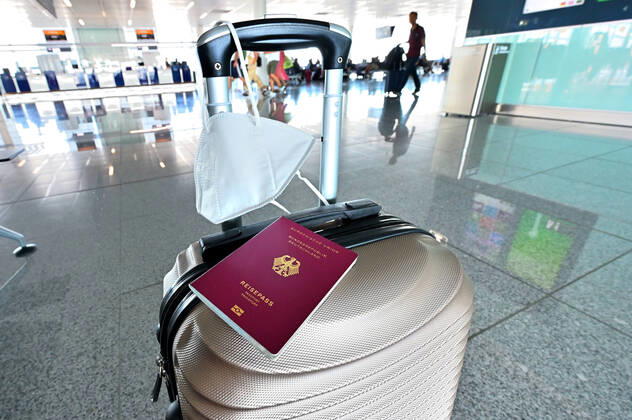 Auf dem Koffer am Flughafen, liegen Reisepass und Mundschutz griffbereit. Im Flugzeug bleibt die Maskenpflicht. München Bayern Deutschland Copyright: xRolfxPossx