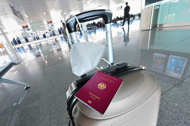 Auf dem Koffer am Flughafen, liegen Reisepass und Mundschutz griffbereit. Im Flugzeug bleibt die Maskenpflicht. München Bayern Deutschland Copyright: xRolfxPossx