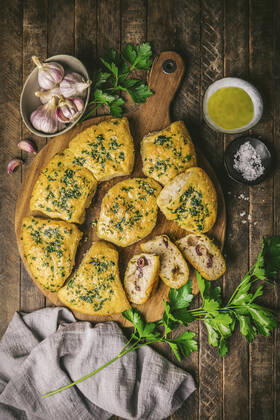 IMAGO Creative, Food, Brot, Knoblauchbrot Overhead of focaccia bread with garlic and olives on a wooden board with raw garlic, parsley and olive oil Overhead of focaccia bread with garlic and olives on a wooden board with raw garlic, parsley and olive oil Copyright: xEmilyxCliftonx EC010822-7