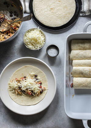 IMAGO Creative, Food, Enchiladas Enchiladas in the making. Tortillas on the plate filled with cheesy chicken and black beans Copyright: xMariaxSamarinaxSquiresx MS240619-25