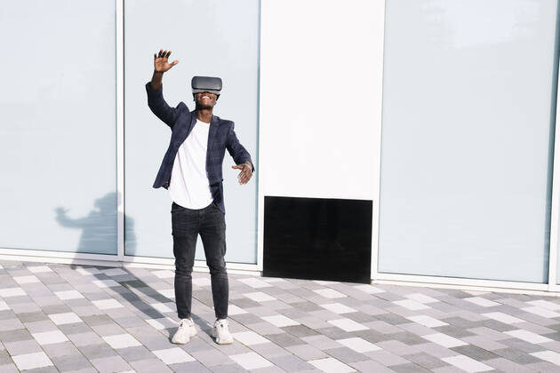 Man with virtual reality simulator gesturing in front of wall model released, Symbolfoto, AMWF00322