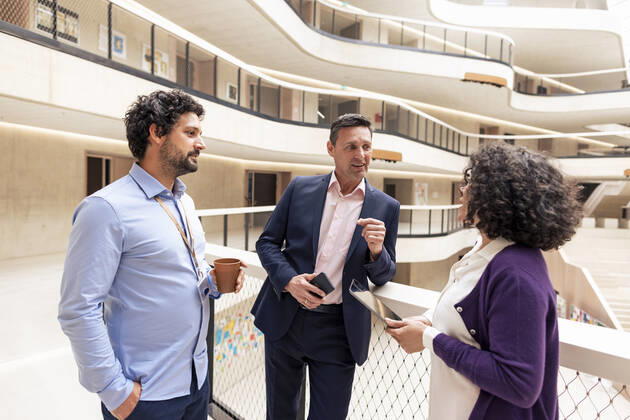 Smiling businessman planning strategy with colleagues in office corridor model released, Symbolfoto property released, JOSEF12674