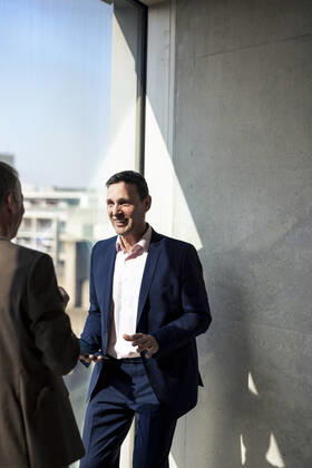 Smiling businessman planning strategy with colleague by window in office model released, Symbolfoto property released, JOSEF12710