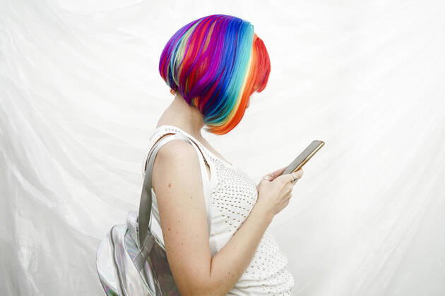 IMAGO Creative: Business, Innovative Technologie-Lösungen Woman with multi colored hair using smart phone by plastic backdrop model released, Symbolfoto, SVCF00141