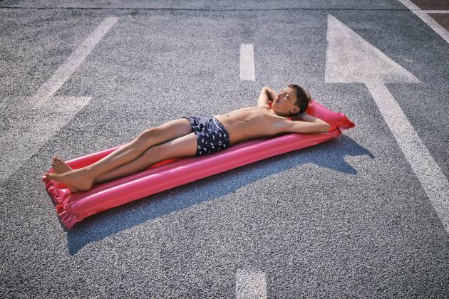 Shirtless boy lying on inflatable pool raft in parking lot model released, Symbolfoto, DIKF00703