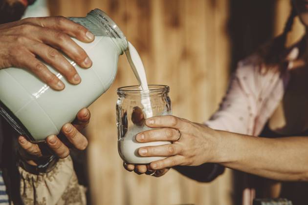 Man pouring fresh milk into glass jar on sunny day model released, Symbolfoto property released, IEF00168