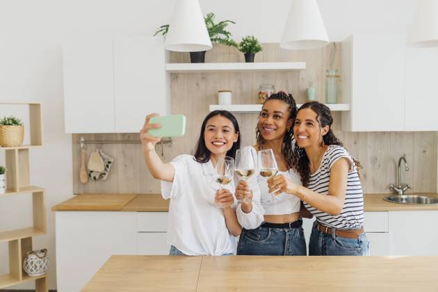 IMAGO Creative, Lifestyle, Leben in einer Wohngemeinschaft, WG Happy friends talking selfie with wineglasses in kitchen model released, Symbolfoto property released, MEUF08058