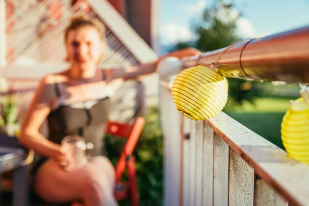 Summer feeling on the balcony: Close up of lampions, smiling girl in the blurry background Close up of summer lampions on a balcony, girl in the blurry background. Leisure time in the summer holidays Copyright: xZoonar.com PatrickxDaxenbichlerx 14031636