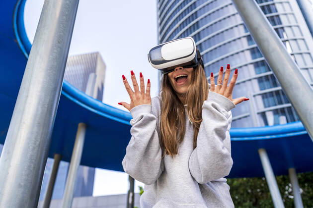 Excited woman wearing virtual reality simulator in front of building model released, Symbolfoto, DLTSF03215
