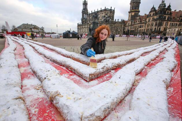 Bilder des Jahres, News 11 November Der groesste Stollen der Welt ist am 26.11.2022 auf dem Theaterplatz vor der Semperoper in Dresden praesentiert und verkauft worden (Foto vom 26.11.2022). Laut Abnahme des Rekordversuches durch das Rekord-Institut Deutschland brachte es das traditionelle Adventsgebaeck am Ende auf eine Laenge von mehr als 1.000 Metern. Hergestellt wurde der rund fuenf Tonnen schwere Striezel vor Hunderten von Zuschauern von der saechsischen Traditionsbaeckerei Emil Reimann, wie der Thueringer Verein Rekordteam als Veranstalter mitteilte. Die Herstellung von Riesenstollen und das Stollenfest haben eine lange Tradition in Dresden. Mit den Einnahmen soll ein sechsjaehriger Junge unterstuetzt werden, der an dem seltenen MED-13 L Syndrom leidet und Autist ist. Copyright: epd-bild MatthiasxSchumann epd-Stollenbacken5 - Kopieren