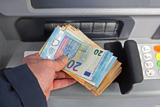 Bargeldversorgung aus einem Automat Eine Person holt an einem Geldautomaten eine größere Menge Bargeld in 50 und 20 Euro Geldscheinen ab