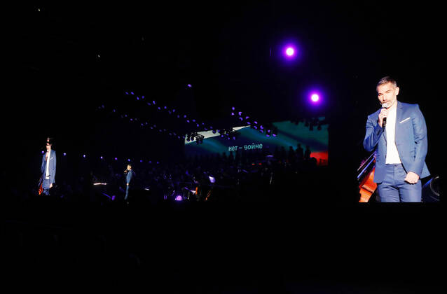 Night of the Proms 2022 13.12.2022, Erfurt, Messehalle, Night of the Proms 2022 Das Antwerp Philharmonic Orchestra und der Chor Fine Fleur unter Leitung der Dirigentin Alexandra Arrieche begleiten die Stars im Bild: Moderator Marcus Fahn auf der Buehne, im Hintergrund ist fuer einen Moment die russische Flagge eingeblendet, darauf steht in kyrillischen Buchstaben Nie wieder Krieg