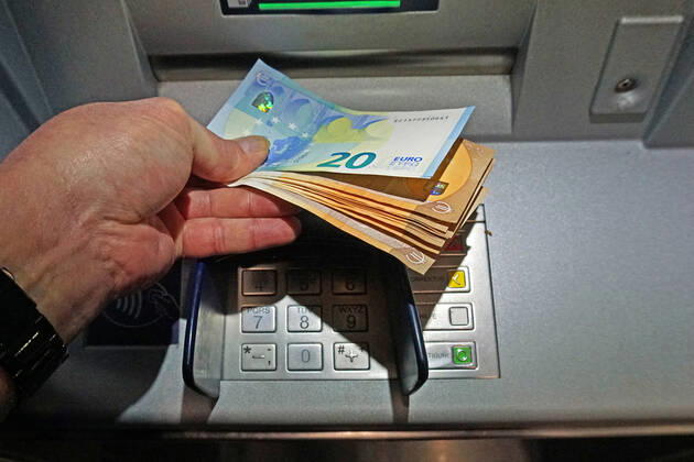 Bargeldversorgung aus einem Automat Eine Person holt an einem Geldautomaten eine größere Menge Bargeld in 50 und 20 Euro Geldscheinen ab