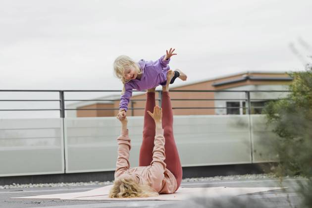 IMAGO Creative, Urban Lifestyle Mother balancing girl on legs lying down at rooftop model released, Symbolfoto, München Bayern Deutschland Gertrud-Grunow-Strasse AANF00412