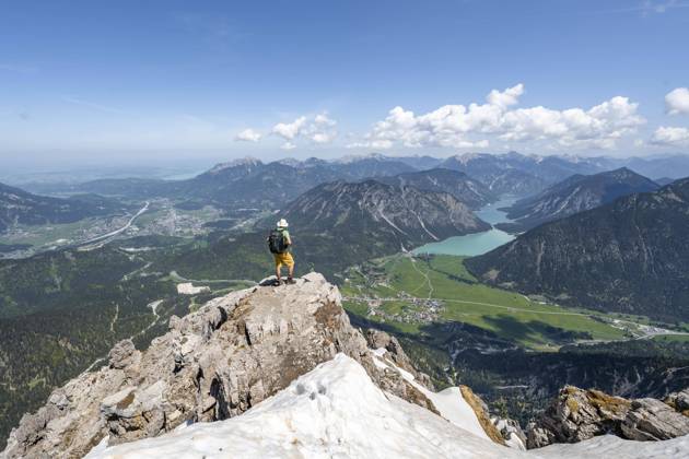 Wanderer am Gipfel des Thaneller, Ausblick auf Berge mit Plansee und Ort Reutte, Berglandschaft, Lechtaler Alpen, Tirol, Österreich, Europa