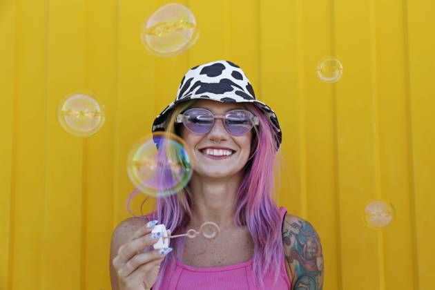 Happy woman holding bubble wand in front of yellow wall model released, Symbolfoto property released, SYEF00145