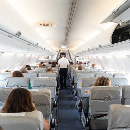 Interior of commercial airplane with passengers on their seats during flight. Interior of commercial airplane with unrecognizable passengers on their seats during flight. Steward in blue white uniform walking the aisle of commercial airplane. Copyright: xZoonar.com MatejxKastelicx 13041244