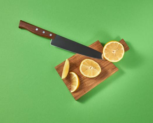 Half and slices of fresh tropical yellow lemon on a wooden cutting brown board with a steel knife. View from above. Top view of halfs and slices of natural lemon on a cutting wooden board. A sharp steel knife is cut by organic citrus fruit. Copyright: xZoonar.com IaroslavxDanylchenkoxphoographerxxartjazz.com.uax 12388467