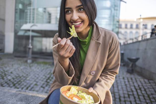 Happy young woman eating lunch sitting outside building model released, Symbolfoto, JCCMF08943
