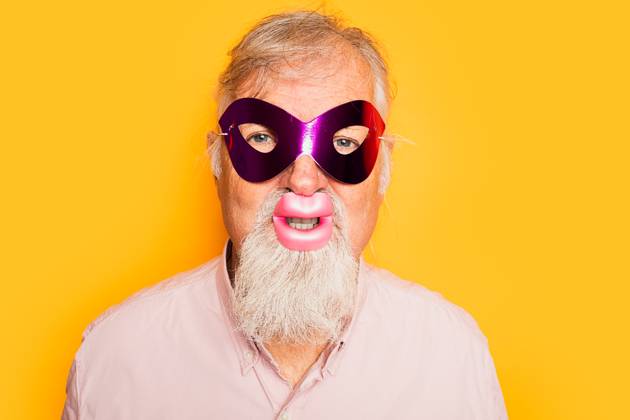 IMAGO Creative, Gesellschaft, Fasching Positive bearded aged male in pink shirt wearing carnival mask and funny lips looking at camera on yellow background, Model released HodeiUnzueta_ID12634_384197_009 Copyright: xHodeixUnzuetax MR