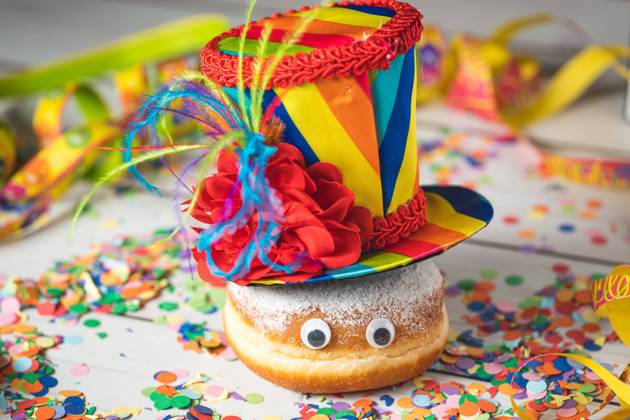 Krapfen Berliner dekoriert zu Rosenmontag, Fasching oder Karneval mit Luftschlangen, Kostüm und Konfetti