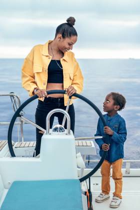 Cheerful African American mother and son standing together at steering wheel while looking at each other during weekend on yacht, Model released AlfonsoSaenz_ID12778_387464_047 Copyright: xAlfonsoxSaenzx MR