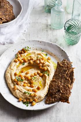 IMAGO Creative, Food, Hummus Top view of delicious hummus with chickpeas seeds and olive oil served on plate with crispy healthy crackers on table in kitchen GeorgiaGold_ID12873_391219_002 Copyright: xGeorgiaxGoldx Model Released