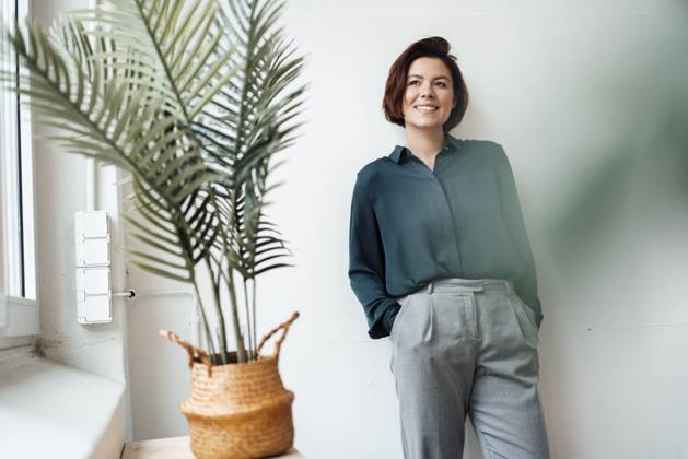 Thoughtful businesswoman standing with hands in pockets at office model released, Symbolfoto property released, JOSEF16037