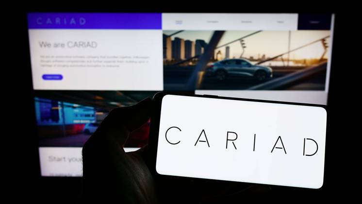 Person holding cellphone with logo of German automotive software company Cariad SE on screen. Stuttgart, Germany - 10-15-2022: Person holding cellphone with logo of German automotive software company Cariad SE on screen in front of business webpage. Focus on phone display. Copyright: xZoonar.com TimonxSchneiderx 19287755