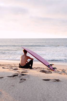 Back view of unrecognizable male surfer with naked torso and surfboard on head sitting on sandy coast and enjoying picturesque seascape during sunset, Model released NicoMortarini_ID13416_408708_014 Copyright: xNicoxMortarinix MR