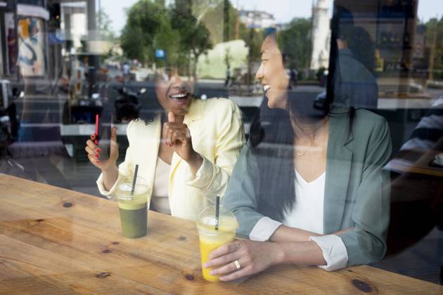 IMAGO Creative, Urban Lifestyle Happy woman talking to friend sitting with juice in cafe seen through window model released, Symbolfoto property released, MMPF00704